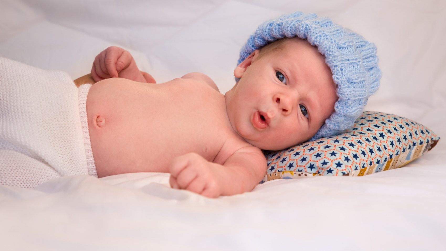 Pablo, un bébé de trois mois allongé sur un lit, fait une grimace