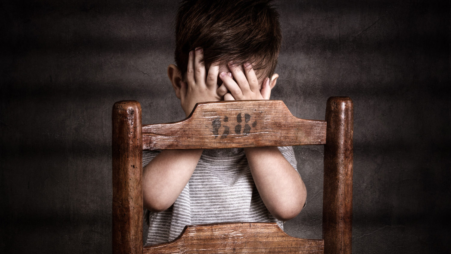 Enfant photographié en studio avec les mains se masquant le visage