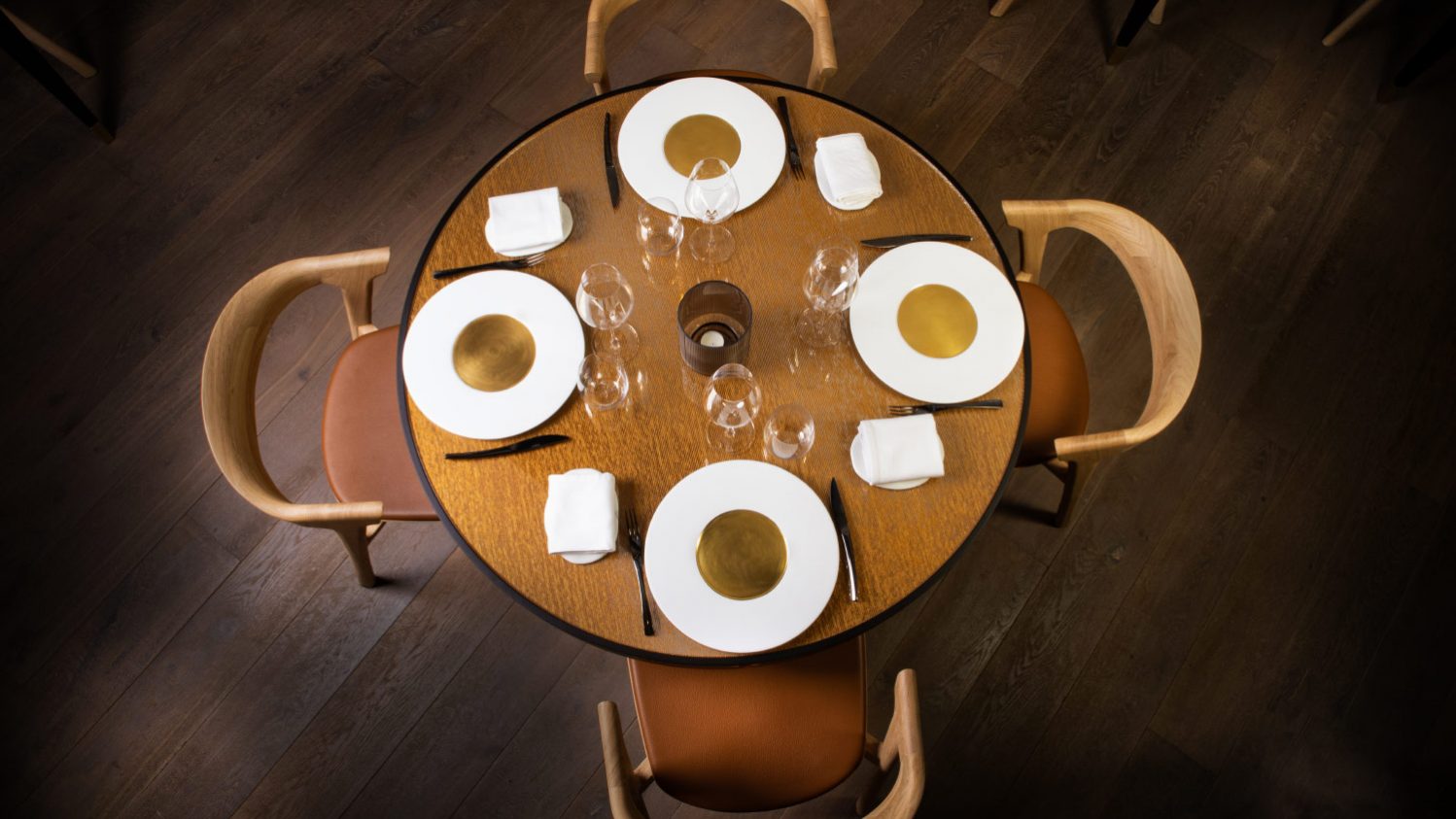 Quatre assiettes avec couverts sur une table ronde vue de dessus