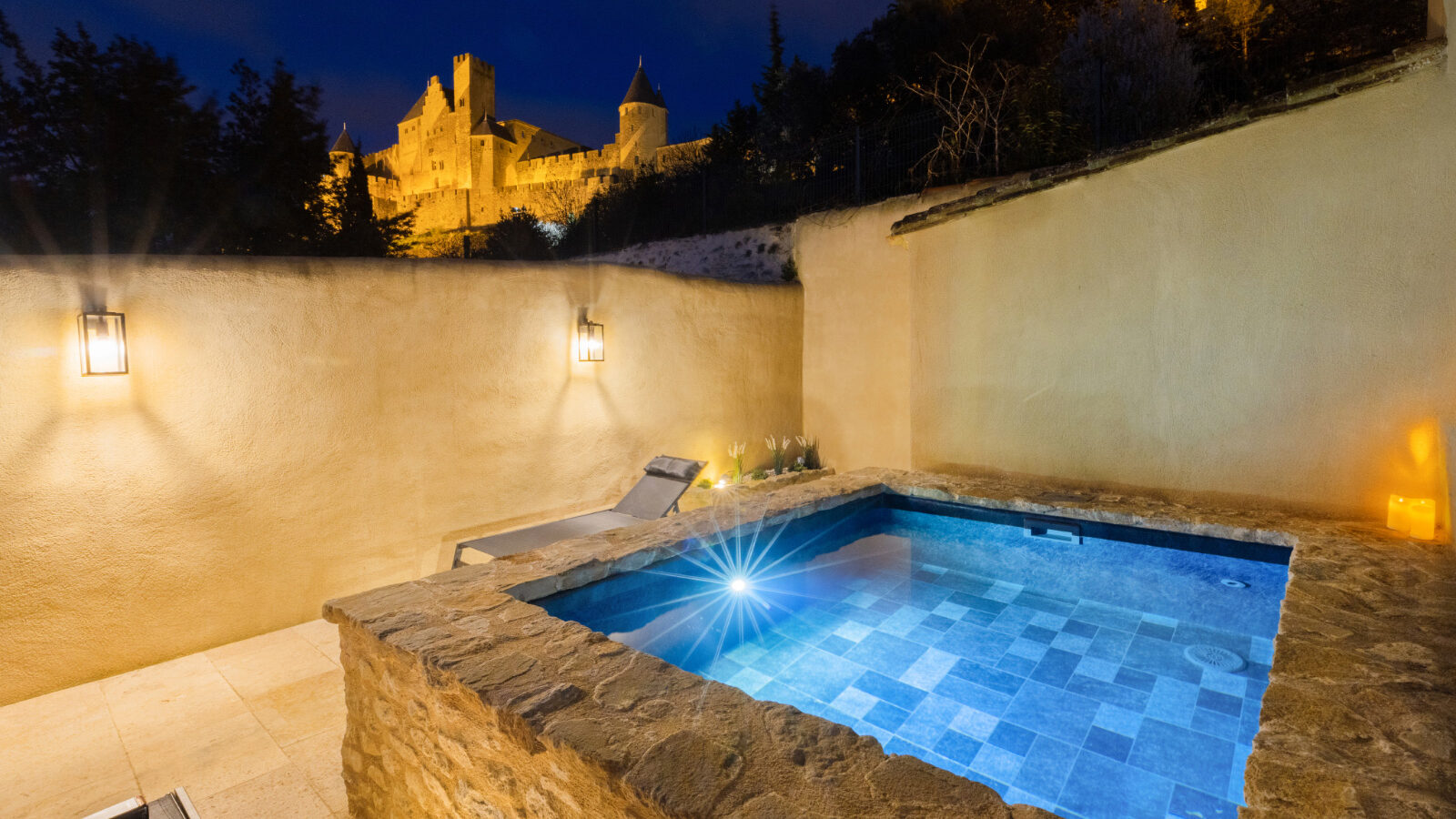 Jacuzzi de nuit sur une terrasse éclairée avec vue sur la cité de Carcassonne