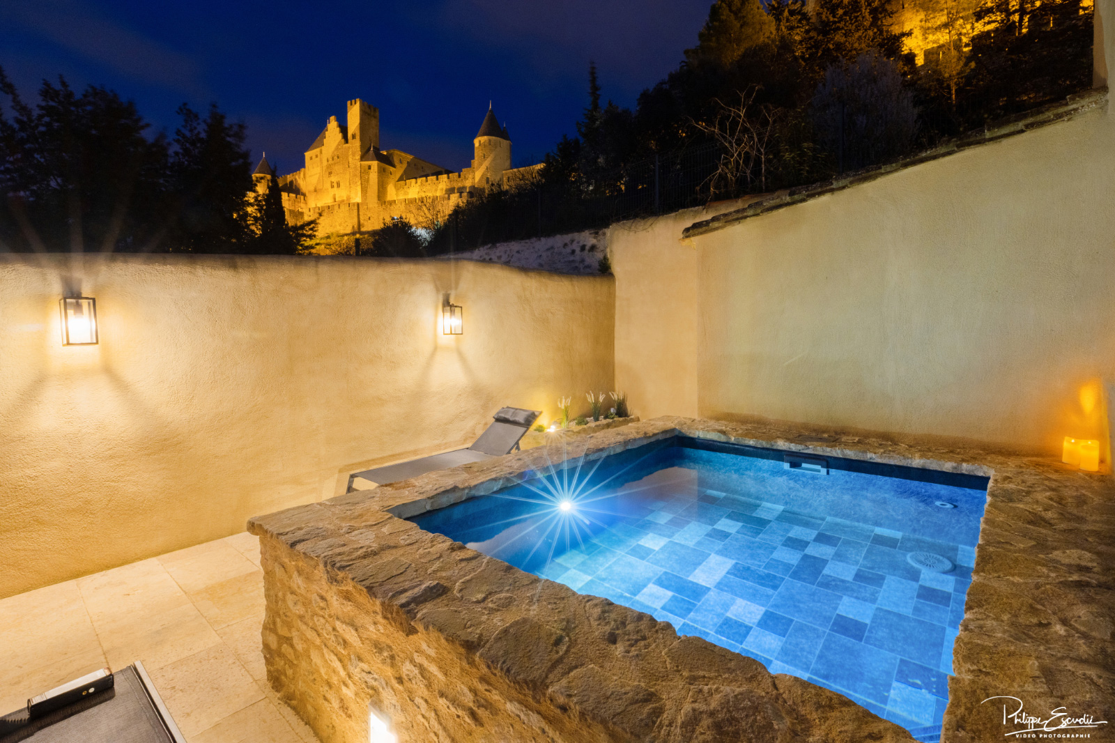 Jacuzzi de nuit sur une terrasse éclairée avec vue sur la cité de Carcassonne